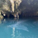 The film on the water's surface is supposedly limestone residue from the drips coming from the ceiling